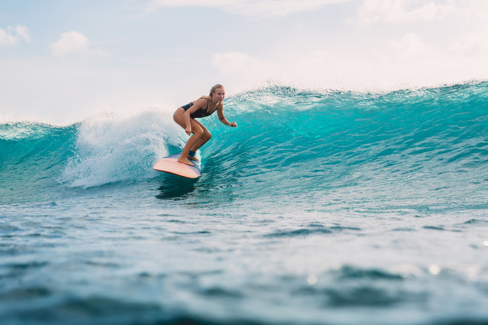 Surf girl on surfboard. Woman in ocean during surfing.